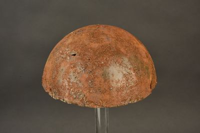 an old helmet on a metal stand against a gray background