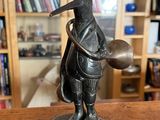 statue d'un homme avec un oiseau sur la tête, tenant un bol