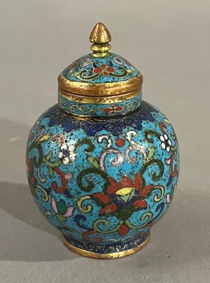 un vase bleu avec un couvercle doré posé sur une table