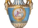 a blue and gold vase with a picture of a woman on it