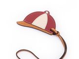 Le petit sac rouge et blanc est muni d'une bandoulière marron et orné d'une voile blanche.
