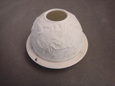 a small white vase on a plate on a table