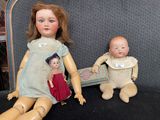 two dolls sitting next to each other on a chair