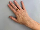 a person ' s hand with a gold ring on it