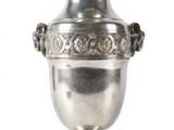 a silver vase that is sitting on a white surface