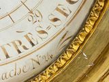 a gold clock with roman numerals on the face