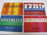 quatre livres posés sur une table, sur fond blanc, avec des couvertures rouges, jaunes, bleues, vertes et orange