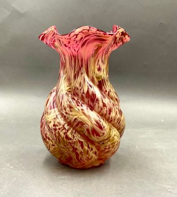un vase rouge et jaune posé sur une surface grise