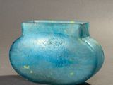 un vase bleu posé sur une table, sur fond gris