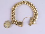 bracelet with a gold chain and a coin on a white surface