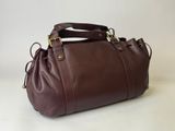 un sac à main en cuir marron posé sur une table blanche
