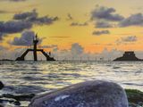 a large rock sitting on the shore of a body of water