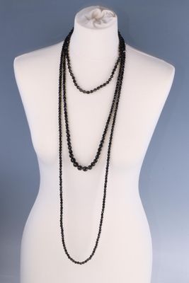 un torse de mannequin sur lequel est posé un collier de perles noires