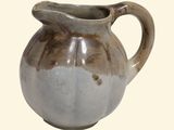 a brown and white pitcher sitting on a white surface