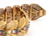 gold bracelet with multi colored stones on a white surface