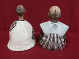 deux figurines en céramique représentant une femme et un homme sur fond rouge
