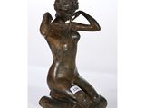 une statue en bronze d'une femme assise sur un rocher