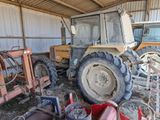 a tractor that is parked in a barn with other machinery
