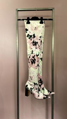 pink and black floral pants hanging on a rack in front of a pink wall