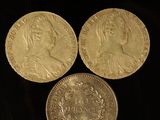 three gold coins sitting next to each other on a black surface