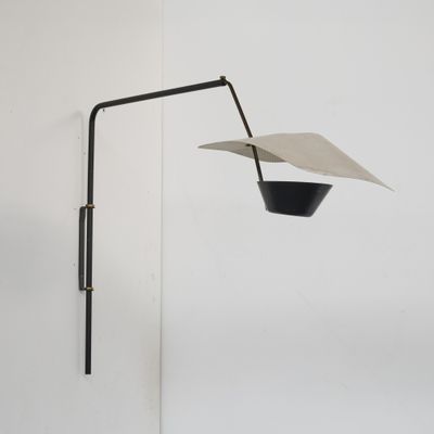 une lampe noire et blanche fixée au mur, d'où pend un morceau de papier