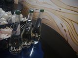 several bottles of water are lined up on a table in front of a surfboard