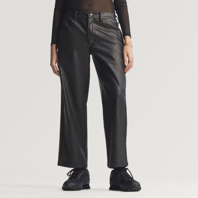 une femme vêtue d'un pantalon en cuir noir et d'un pull à col roulé noir