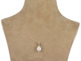 a white pearl and diamond pendant on a mannequin neck
