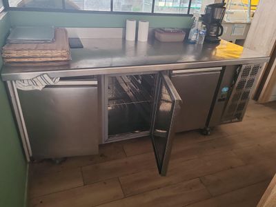 une cuisine équipée d'un plan de travail en inox et d'un réfrigérateur