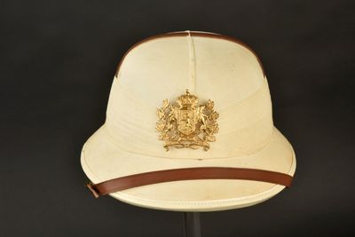 chapeau beige orné d'un ruban en cuir et d'un écusson sur le devant