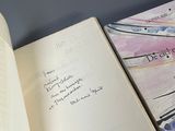 two open books on a table with a pen and paper