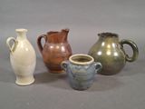 quatre vases de couleurs différentes posés les uns à côté des autres sur une surface grise