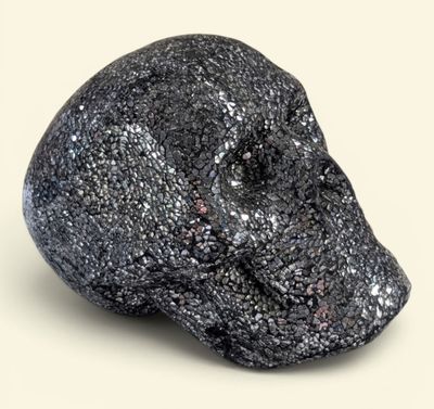 black rock with a skull on top of it sitting on a white surface