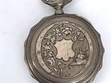 a silver pocket watch with a picture of a coat of arms on it