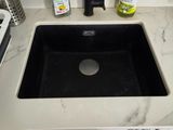 a black sink sitting on a white counter in a kitchen