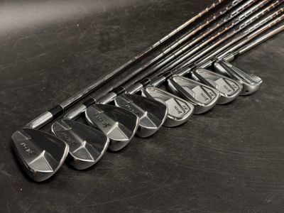 Plusieurs clubs de golf sont alignés sur une surface noire