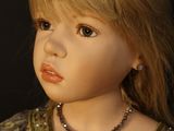 blond haired doll wearing a gold dress and a beaded necklace
