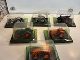six camions miniatures exposés sur une table blanche