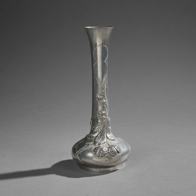 a silver vase sitting on a table with a shadow on the floor