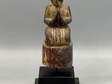 an image of a statue of a person sitting on top of a wooden block