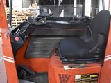 an orange forklift with a black seat in a warehouse