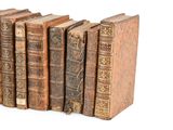 several old books are lined up in a row on a white surface