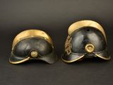 two helmets with gold trims on them sitting on a black surface