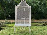 an old white bird cage sitting on top of a lush green field