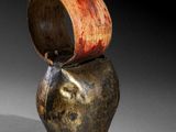 a brown vase with a red handle sitting on top of it