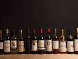 Des bouteilles de vin sont alignées sur une table devant un fond noir.