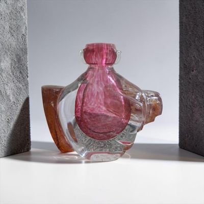 une bouteille en verre rose posée sur une étagère à côté d'un bloc