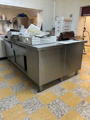une cuisine avec un grand îlot en inox au milieu de la pièce