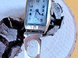 a silver watch sitting on top of a piece of wood