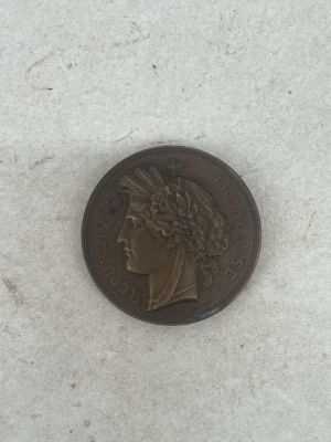 an old coin sitting on top of a white surface next to a piece of paper